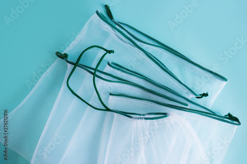 empty white transparent weaving kapron bags for repeated use when buying and storing fruits and vegetables on a blue background. top view close up photo