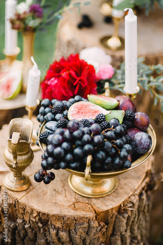 Wedding decor of fruit, flowers and candles on a wooden stump