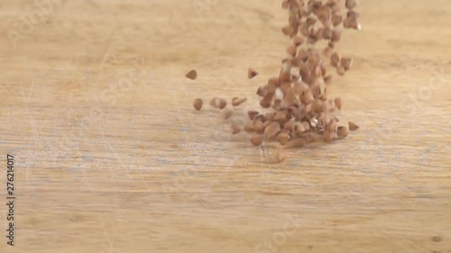 Buckwheat fall on wooden surface. Cereals as main object of plant food of people, biblical food. Abundance of grain as guarantee of absence of hunger on Earth concept. Super slow motion 1000 fps photo