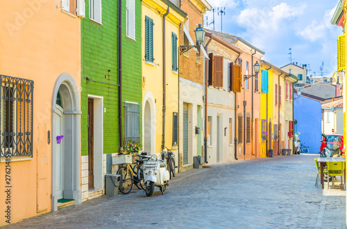 Typical italian old buildings with colorful multicolored walls and traditional houses and motorcycle bike scooter parked on cobblestone street in historical city centre Rimini, Emilia-Romagna, Italy photo