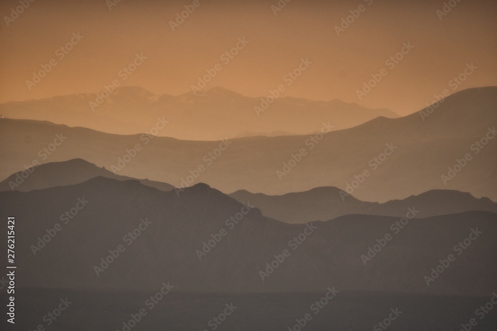Silhouettes of mountains against the background of an orange sky. Sunset in the mountains. Geghama Mountains. Armenia