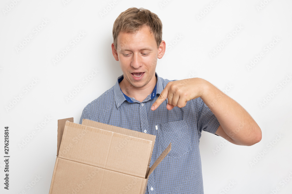 curious man looking inside a cardboard box he holds in his hands on a white background curious man looking inside a cardboard box he holds in his hands on a white background