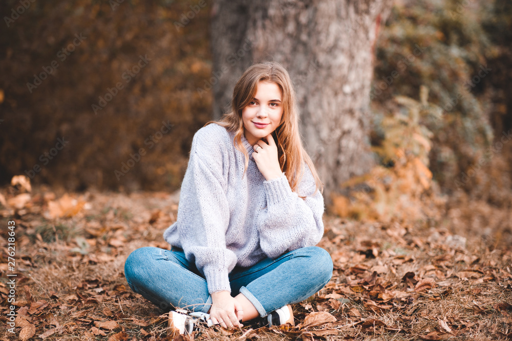 Beautiful teen girl 14-15 year old wearing stylish clothes sitting  outdoors. Looking at camera. Autumn season. Stock Photo