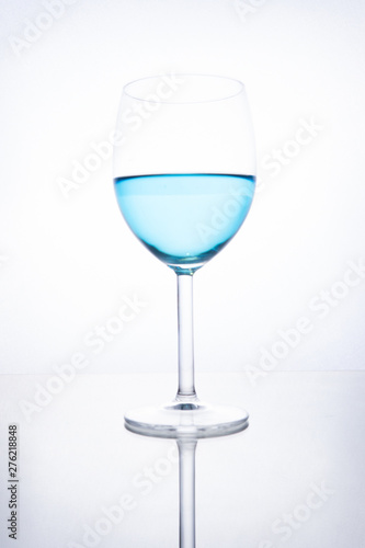 Blue cocktail in a glass on a white background with reflection