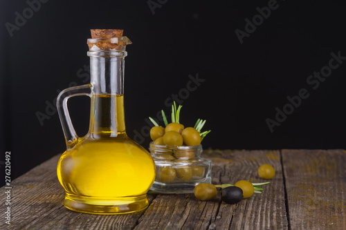 bottle of olive oil, green olives on a black background. Organic olive oil concept