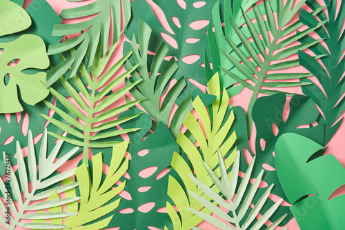 Fototapeta Naklejka Na Ścianę i Meble -  top view of scattered green palm leaves on pink background with copy space