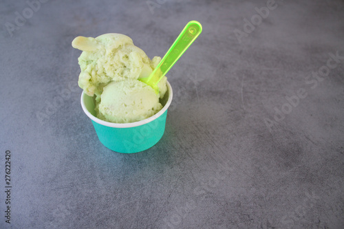 green Apple ice cream sorbet in a turquoise paper Cup on a gray stone table