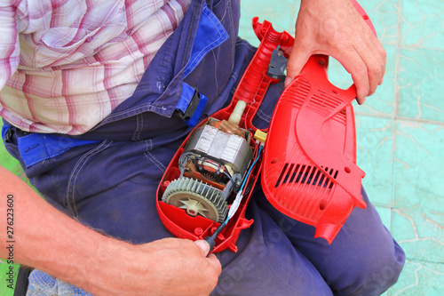 Man repairing an electric trimmer. Close-up. Background.