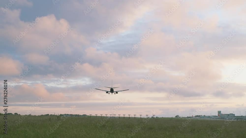 Airplane flying over green meadow & lowering for landing at airport Airplane flying over green meadow & lowering for landing at airport