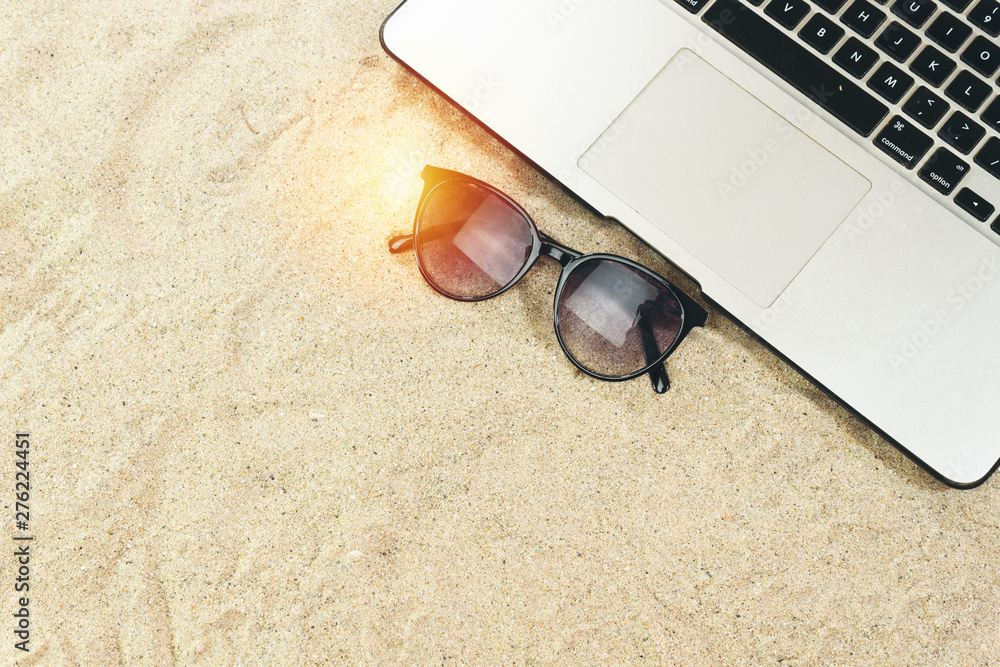 Laptop and black eyeglasses on the beach in summer time Laptop and black eyeglasses on the beach in summer time