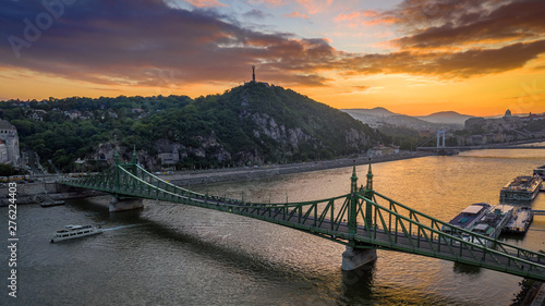 Budapest, Hungary - Aerial skyline view of a beautiful sunset over River Danube and Gellert Hill with sightseeing boat, Liberty Bridge, Buda Castle and Statue of Liberty at background