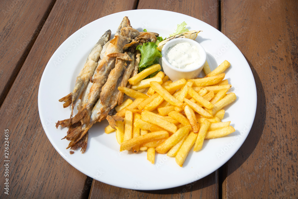 fried far Eastern smelt with potatoes and lemon on a wooden table fried far Eastern smelt with potatoes and lemon on a wooden table