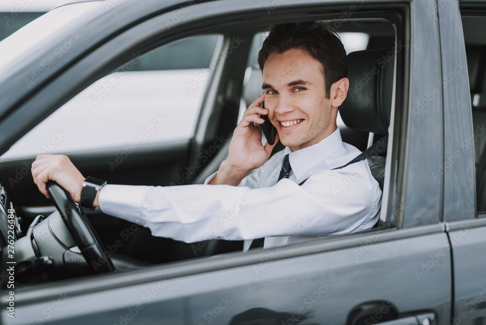 Happy young man sitting in his auto with smartphone Happy young man sitting in his auto with smartphone