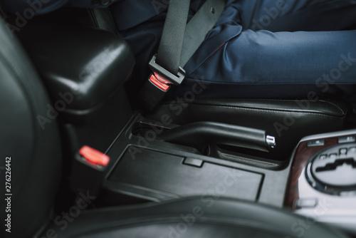 Man in suit using seat belt in his auto