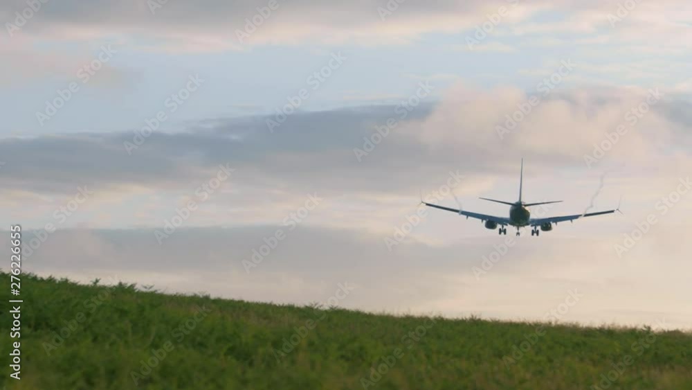 Airplane flying over green meadow & lowering for landing at airport Airplane flying over green meadow & lowering for landing at airport