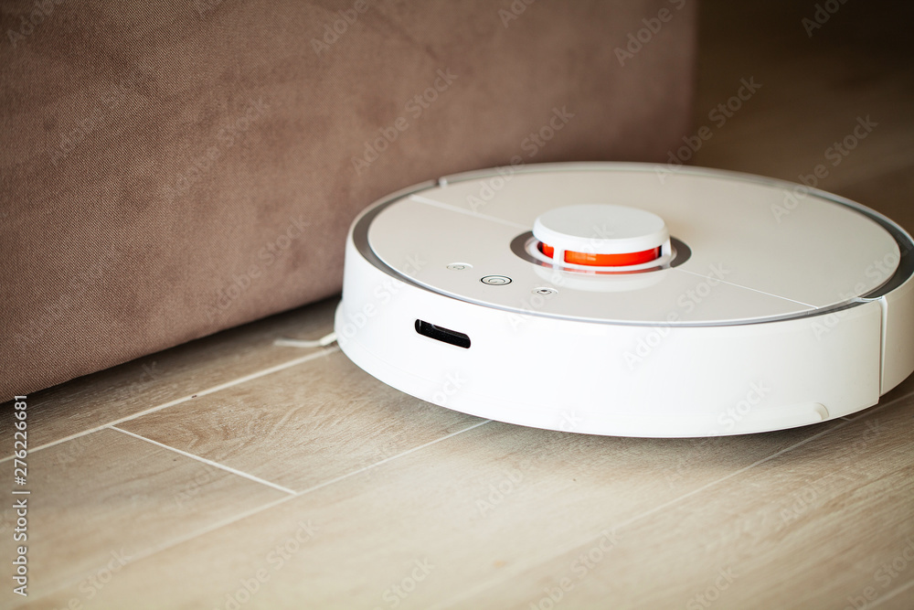 Smart House. Vacuum cleaner robot runs on wood floor in a living room. Smart House. Vacuum cleaner robot runs on wood floor in a living room.