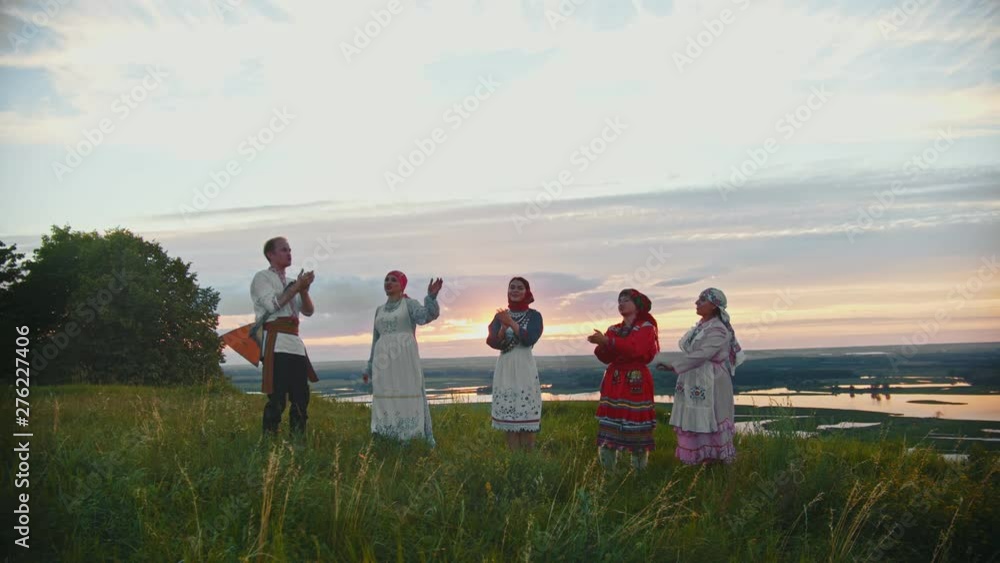 Young people in russian traditional clothes having fun on the field - dancing and clapping their hands Young people in russian traditional clothes having fun on the field - dancing and clapping their hands