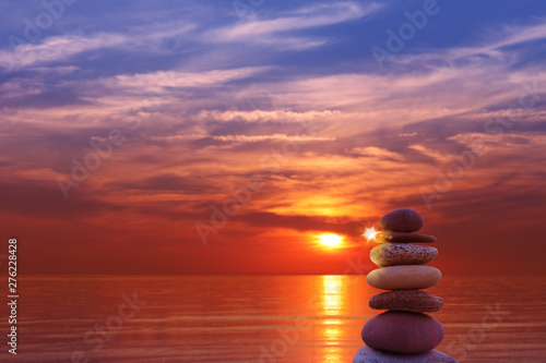 Pyramids of stones in the sand symbolizing Zen, harmony, balance. ocean at sunset in the background