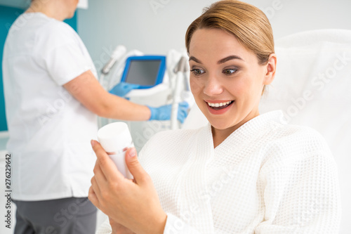 Excited woman looking at the gel for laser treatment