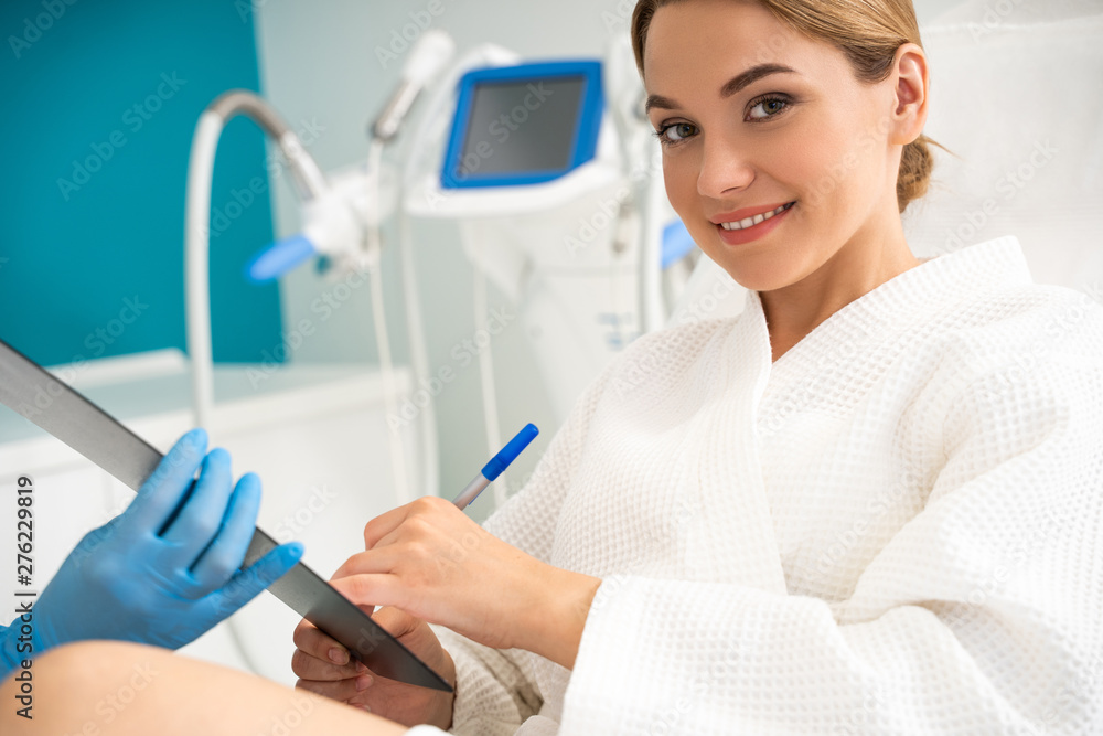 Confident patient smiling to camera and signing the papers Confident patient smiling to camera and signing the papers
