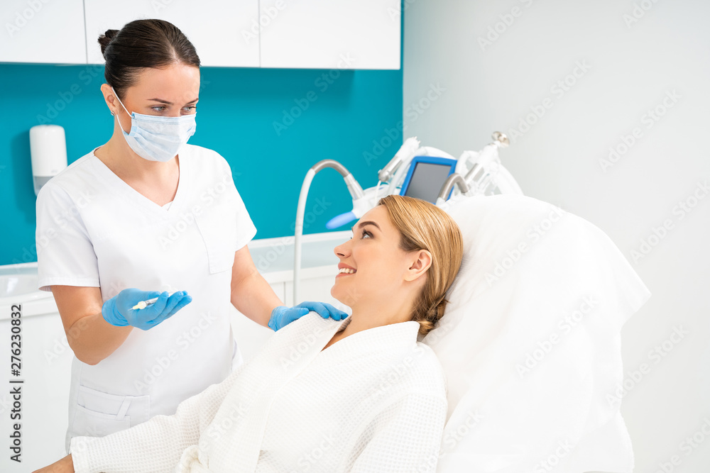 Half length of beautician looking at client in cosmetology office Half length of beautician looking at client in cosmetology office