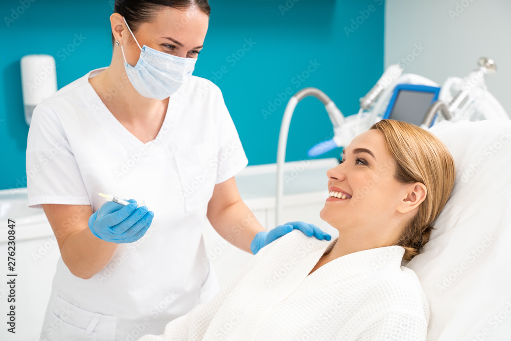 Half length of beautician looking at client in cosmetology office Half length of beautician looking at client in cosmetology office