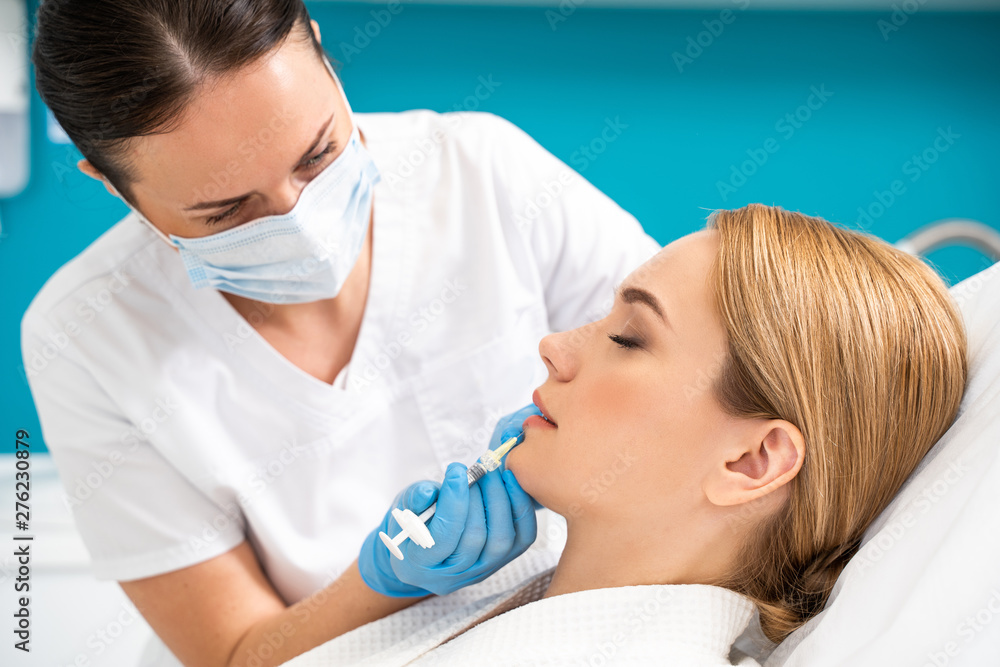 Half length of beautician looking at client in cosmetology office Half length of beautician looking at client in cosmetology office