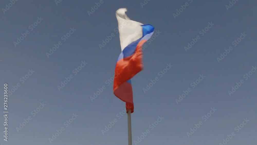 Russian flag on the flagpole waving in the wind against a blue sky with clouds. Russian flag on the flagpole waving in the wind against a blue sky with clouds.