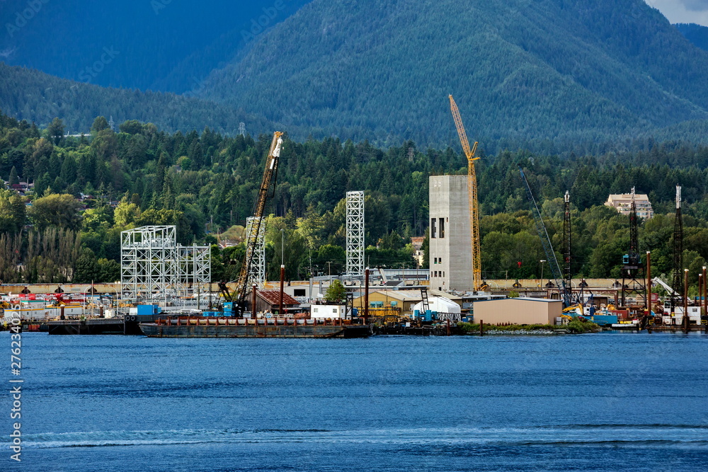 The urban landscape of North Vancouver and the North Vancouver Sea Port, the industrial zone of the Vancouver harbor at the background of a mountain ridge and cloudy sky