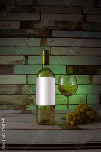 Fototapeta Naklejka Na Ścianę i Meble -  Fresh green environment for a white wine that sweats in the cold with the right temperature to be served in a glass accompanied by a bunch of white grapes