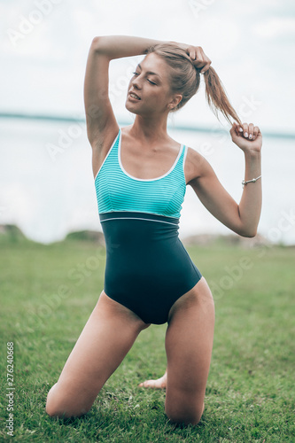 sexy girl on the lawn by the water.girl in a sports swimsuit