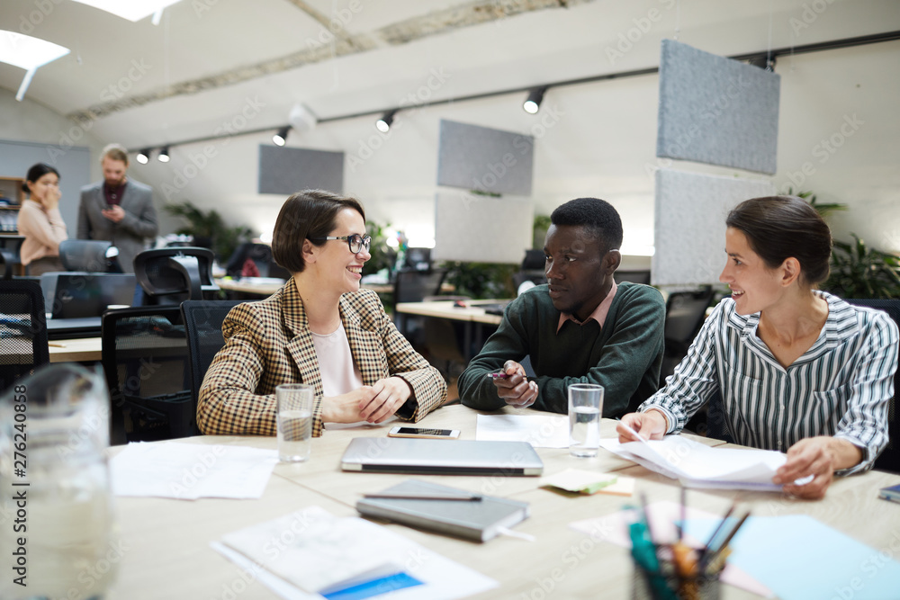 Multi-ethnic group of smiling business people working together in office, copy space Multi-ethnic group of smiling business people working together in office, copy space