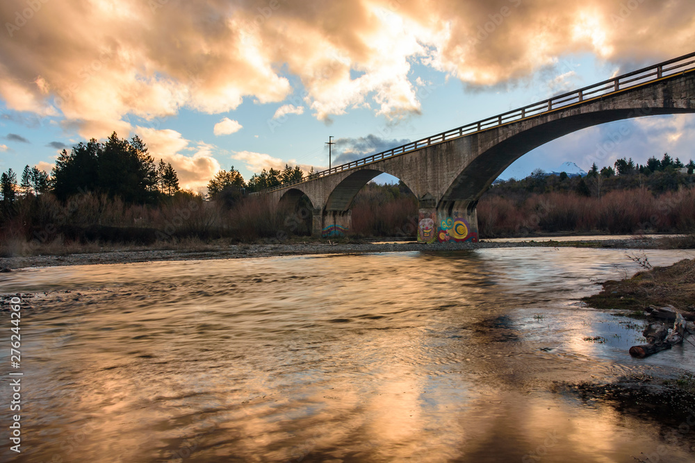 Fototapeta premium Kansas bridge in Trevelin, Chubut over the river against colorful sky