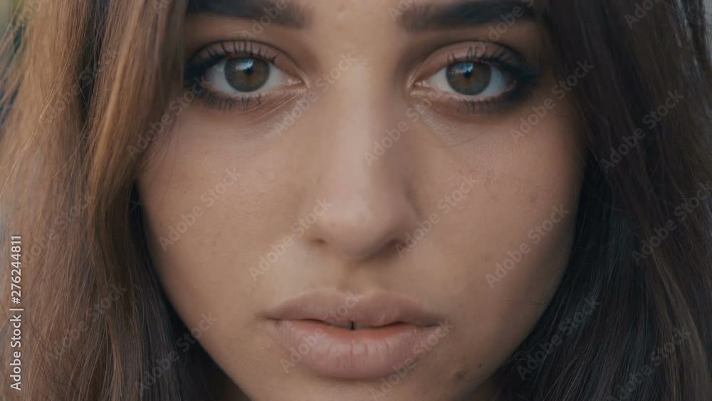 Close-up portrait of beautiful young woman brunette model looking at the camera on a city street background. Girl with big eyes. Close-up portrait of beautiful young woman brunette model looking at the camera on a city street background. Girl with big eyes.
