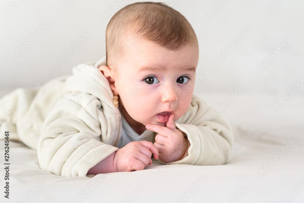 Beautiful and sweet newborn baby lying face down on the bed raising his head to look at the camera curiously. Beautiful and sweet newborn baby lying face down on the bed raising his head to look at the camera curiously.