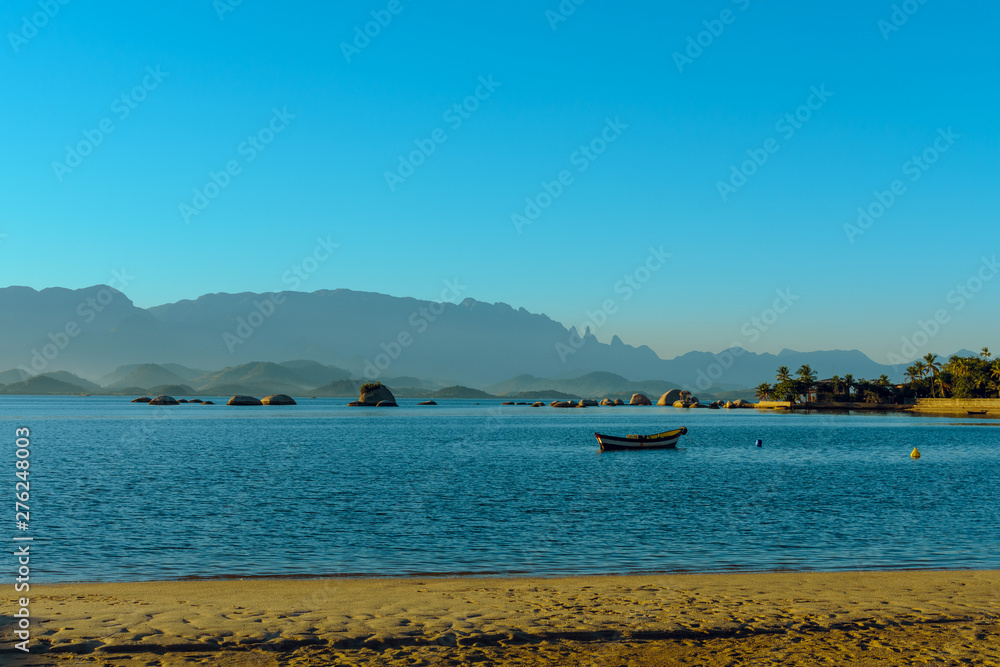 Fototapeta premium Sunset at Paqueta Beach in Rio de Janeiro with mountains in the background
