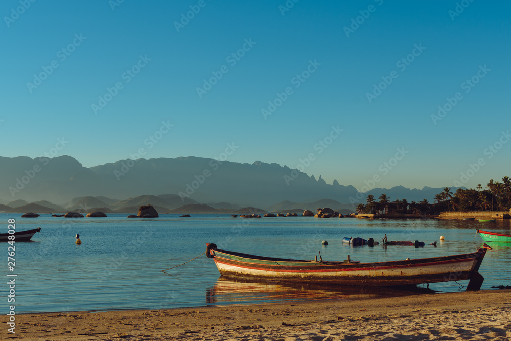Sunset at Paqueta Beach in Rio de Janeiro with a boat in the foreground and mountains in the background