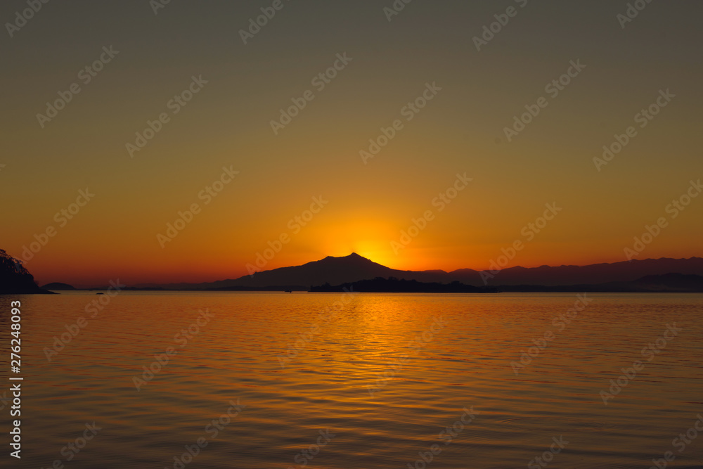 Sunset at Paqueta Island in Rio de Janeiro with silhouettes of mountains on the horizon
