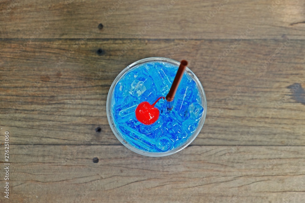 Refreshing blue hawaii italian soda with cherry on top on wooden table, top view. Refreshing blue hawaii italian soda with cherry on top on wooden table, top view.