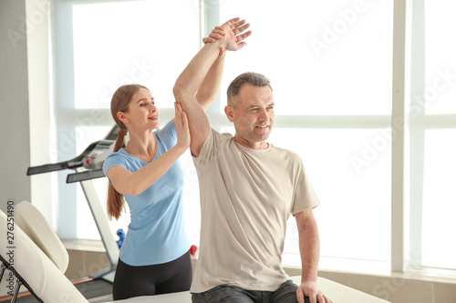 Physiotherapist working with mature patient in rehabilitation center photo
