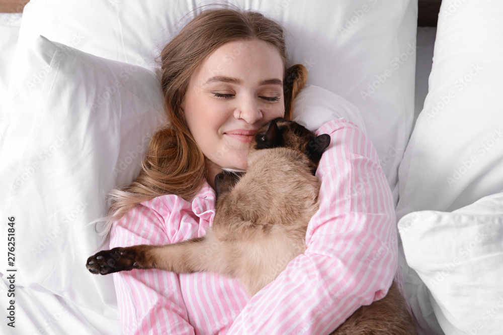 Young woman with cute Thai cat in bedroom Young woman with cute Thai cat in bedroom