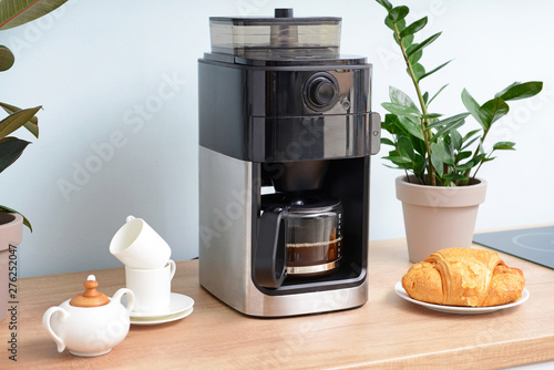 Cuadro en lienzo Modern coffee machine, cups and croissants on kitchen table