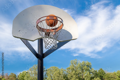 Outdoor basketball hoop with blue sky, Basketball going into hoop scoring photo