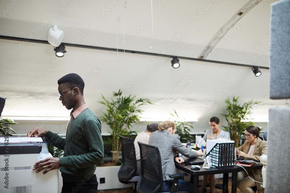 Side view portrait of African businessman scanning documents while working in office, copy space