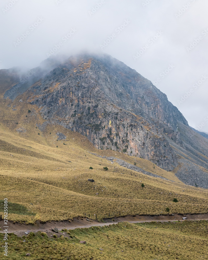 Fototapeta premium Volcano mountain peak on cloudy day with dirt road