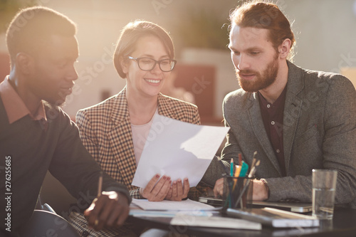 Warm toned portrait of group of business people working in cafe lit by sunlight