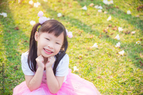 Little asian girl sitting and smiles on grass field in park