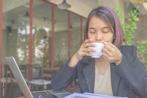 Businesswoman closing eyes enjoy hot cappuccino while working