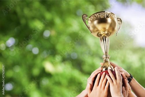 Hands holding golden trophy on light background