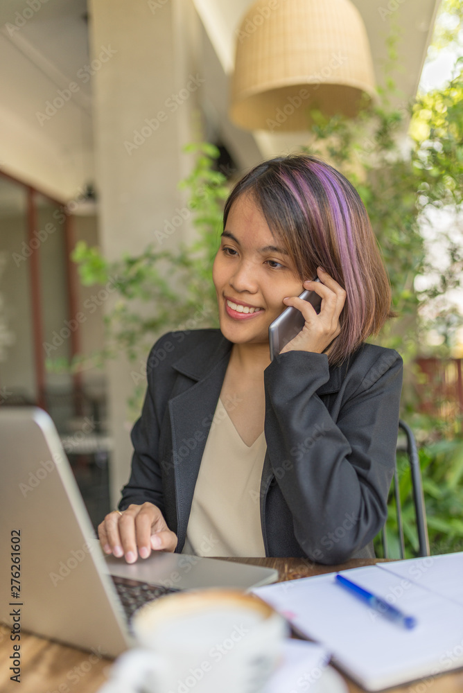 Smiling woman using cellphone and laptop while working Smiling woman using cellphone and laptop while working